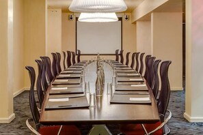A conference room with a long table, chairs, a projector screen, and a chandelier. - Protea Hotel Fire & Ice! Cape Town (Cape Town)