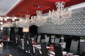 Ein Restaurant mit mehreren Tischen, Stühlen und Kristallleuchtern.