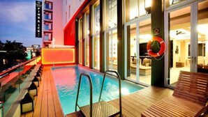 Un espace aménagé au bord de la piscine, comprenant une bouée de sauvetage, une terrasse en bois et une rambarde en verre.