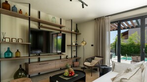 A modern living room with a TV, wooden shelves, a dining area, and a view of a pool.