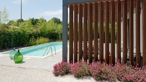 A modern outdoor pool area with a wooden fence, a clear blue pool, and surrounding greenery.