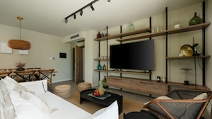 A modern living room with a sofa, coffee table, and a TV mounted on a wooden wall.