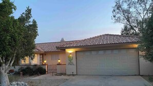 Ein Wohnhaus mit Ziegeldach, Garage und einem gepflegten Vorgarten mit Baum und Kakteendekoration.