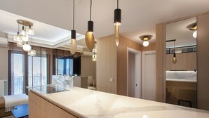 A modern kitchen with a marble countertop, pendant lighting, and wooden cabinetry. - Apartment Skopje Diamond  View (Skopje)