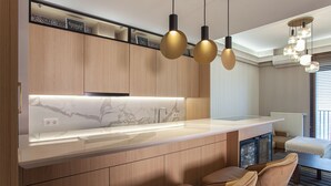 Una cocina moderna con encimera de mármol, armarios de madera e iluminación colgante.