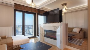 A modern living room with a fireplace, a large TV, and a balcony with a city view. - Apartment Skopje Diamond  View (Skopje)