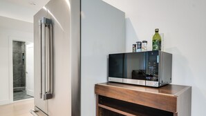Eine moderne Küche mit einem Edelstahl-Kühlschrank, einer Mikrowelle und einem Holzschrank mit Aufbewahrungsbehältern.