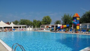 Una piscina con tobogán y sillas de descanso.