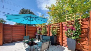 An outdoor patio with a wooden fence, a blue umbrella, and potted plants. - Walk to UC Davis Medical Center! Duplex w/ Patio (Sacramento)