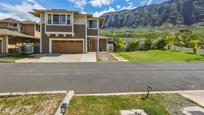 Une maison à deux étages avec un garage, une allée et une pelouse bien entretenue.