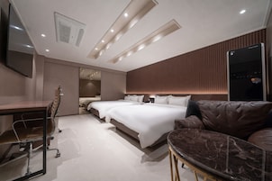 A modern hotel room with a large bed, a desk, a chair, and a flat-screen TV.