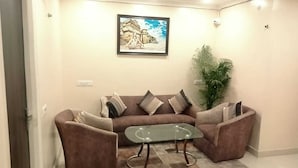 A living room with a brown sofa, a glass coffee table, and a framed picture on the wall. - Coco Inn Homestay  (Varanasi)