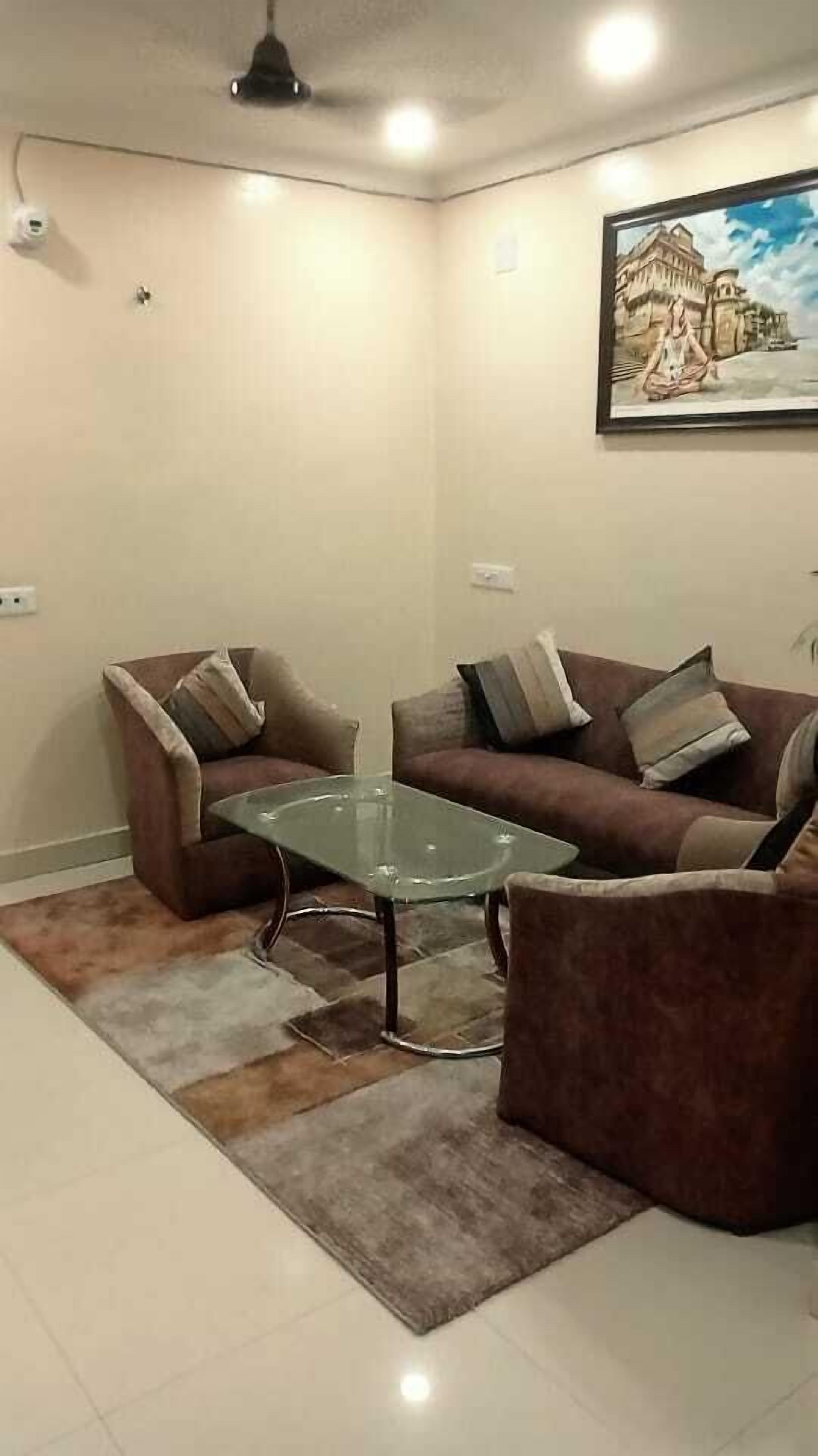 Una sala de estar con una mesa de centro de vidrio, dos sofás marrones y un tapete estampado.