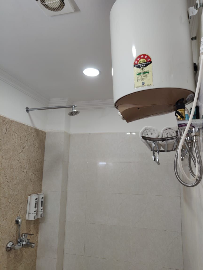Un baño con ducha, toallero y calentador de agua.