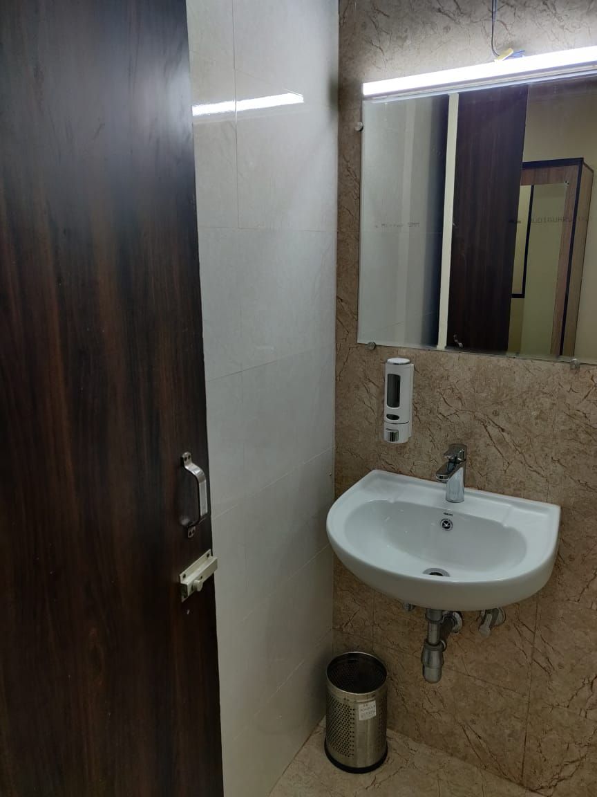 Un baño con un lavamanos blanco, un espejo y un cubo de basura.