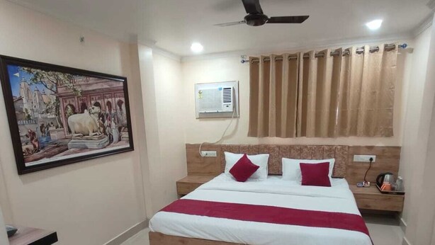 A bedroom with a large bed, a ceiling fan, an air conditioning unit, and a framed picture on the wall. - Coco Inn Homestay  (Varanasi)