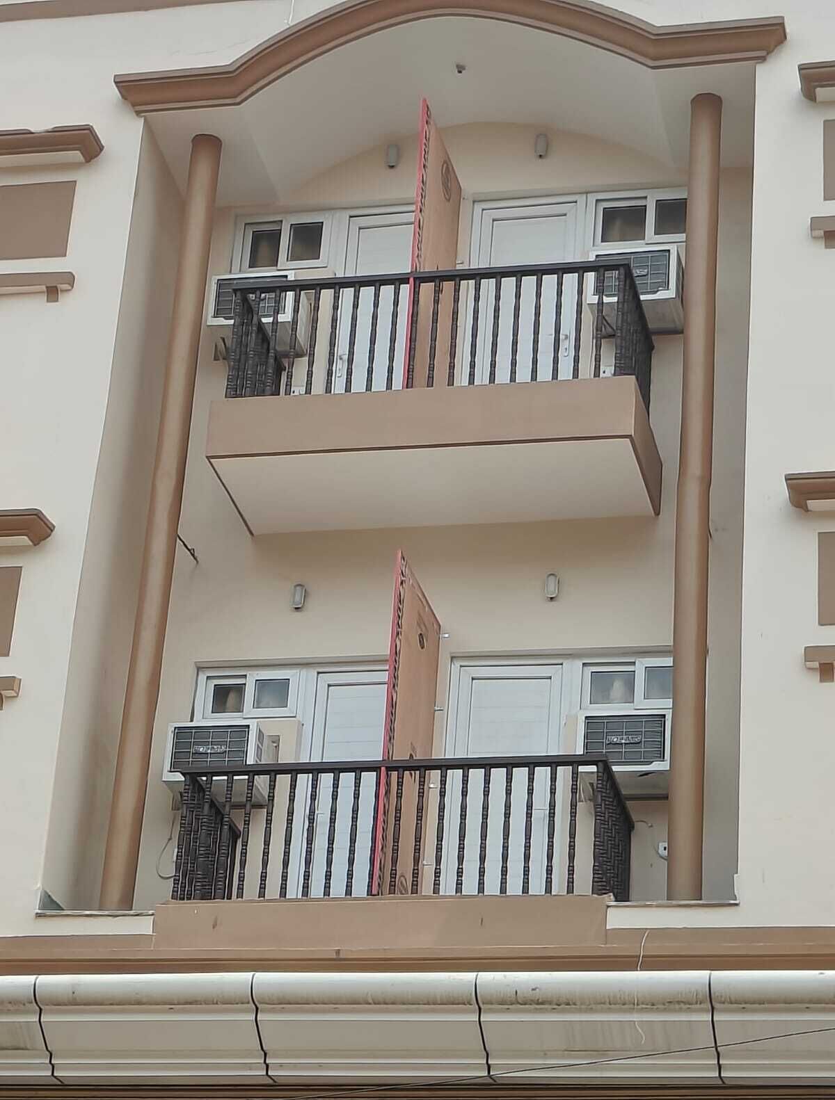 Een meerhoog gebouw met balkons, airconditioners en een centrale kolom.