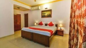 A bedroom with a bed, bedside tables, a ceiling fan, and a painting on the wall. - Joy Guest House (Calangute)