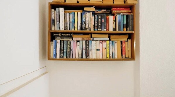 Ein Bücherregal mit einer Auswahl an Büchern an einer weißen Wand.