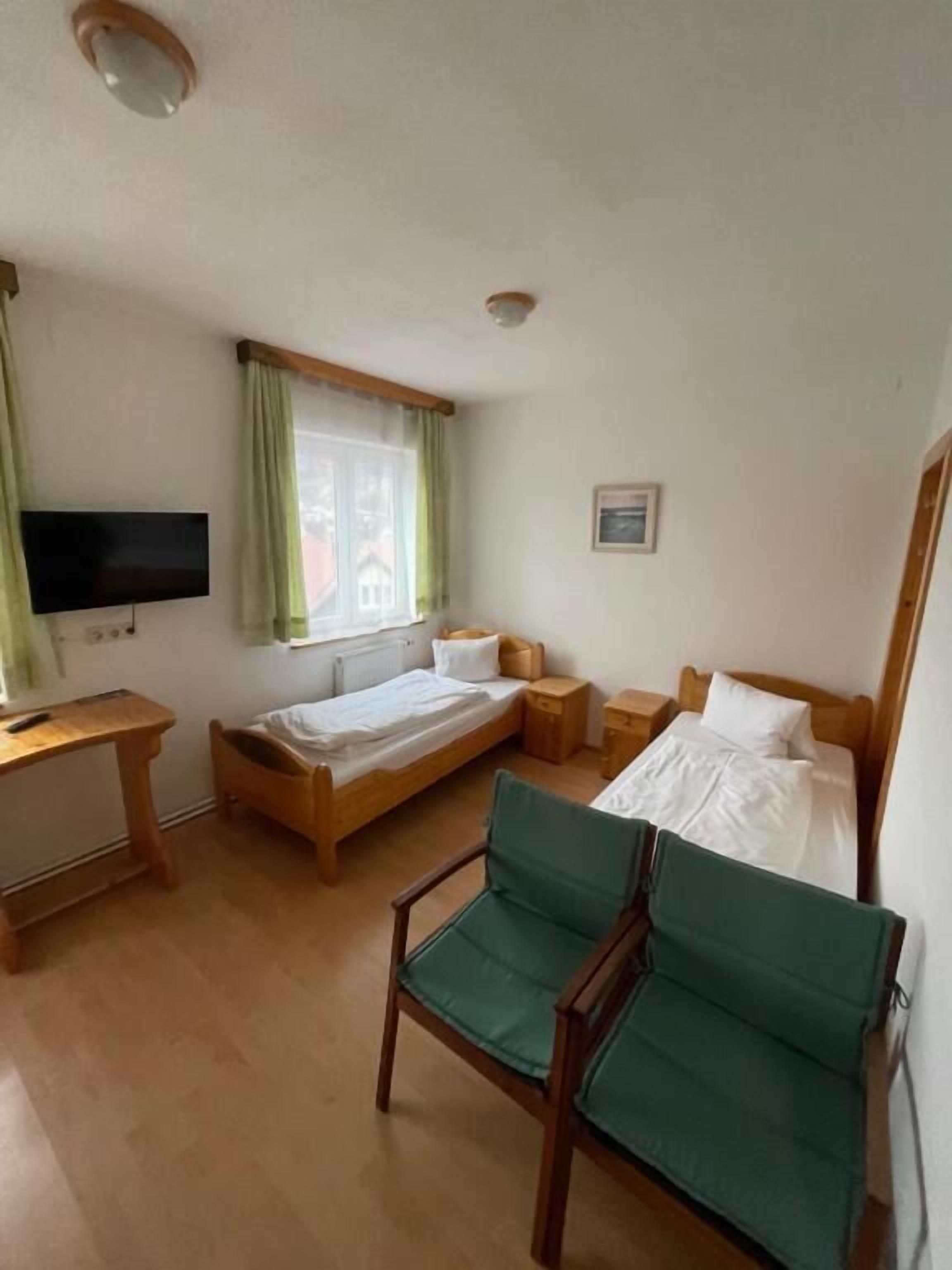 Ein Hotelzimmer mit Bett, Schreibtisch, Stuhl, Fernseher und einem Fenster mit Vorhängen.