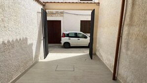 En smal flisebelagt gang, der fører til en hvid bil parkeret i en garage.