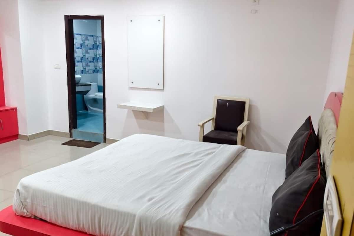 A modern hotel room with a large bed, a small desk, and a chair.