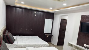 Quarto de hotel com duas camas, televisão, espelho e guarda-roupa.