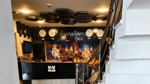 Uma área de recepção com piso de madeira, escada e parede com relógios e um mural de cavalos.