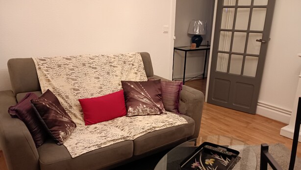 A living room with a sofa, a glass coffee table, and a small side table with a lamp. - LUXURY APARTMENT (Vichy)