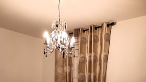 A bedroom with a bed, a chandelier, curtains, and a radiator. - LUXURY APARTMENT (Vichy)