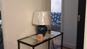 A small room with a glass-top table, a blue lamp, and a door leading to another room. - LUXURY APARTMENT (Vichy)
