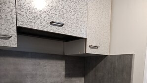 A modern kitchen with a black stovetop, grey cabinets, and a white countertop. - LUXURY APARTMENT (Vichy)