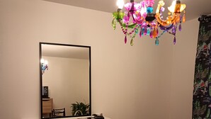 A living room with a white fireplace, a flat-screen TV, a mirror, and a colorful chandelier. - LUXURY APARTMENT (Vichy)