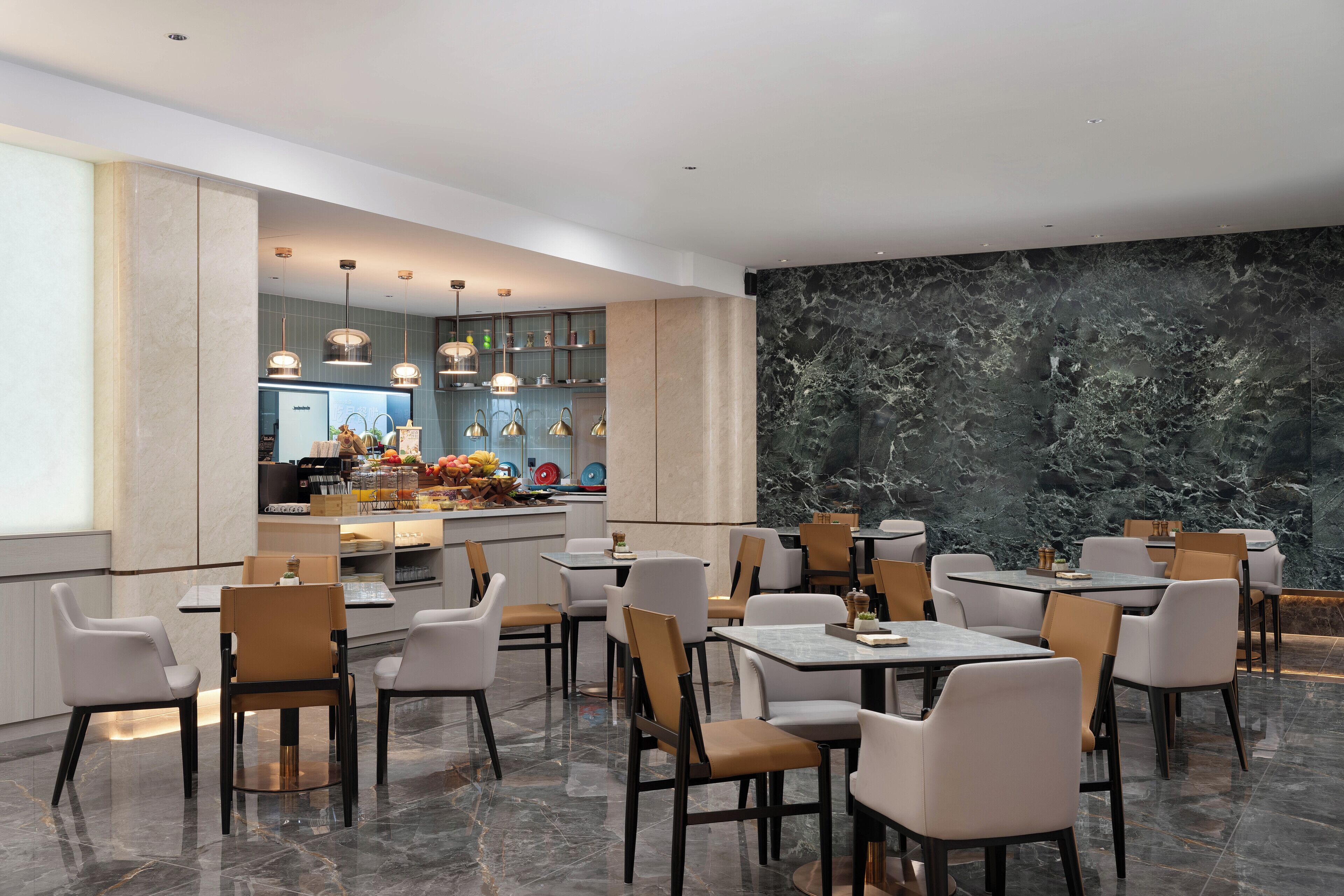A modern restaurant with marble flooring, contemporary furniture, and a central island with a kitchen.