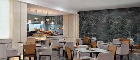 A modern restaurant with marble flooring, contemporary furniture, and a central island with a kitchen.