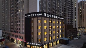 A hotel with a modern facade, multiple windows, and a sign in a foreign language. - Wanda Yuehua Hotel Tangshan North (Tangshan)