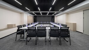 A conference room with a long table, black chairs, and a modern ceiling design. - Wanda Yuehua Hotel Tangshan North (Tangshan)