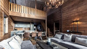 L’intérieur de cette vaste cabane en rondins comprend un espace nuit en mezzanine, un coin repas et un salon aménagé avec des canapés et une table basse.