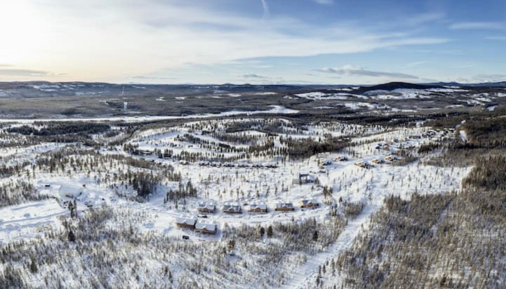 A snow-covered landscape with a small settlement of cabins and buildings.