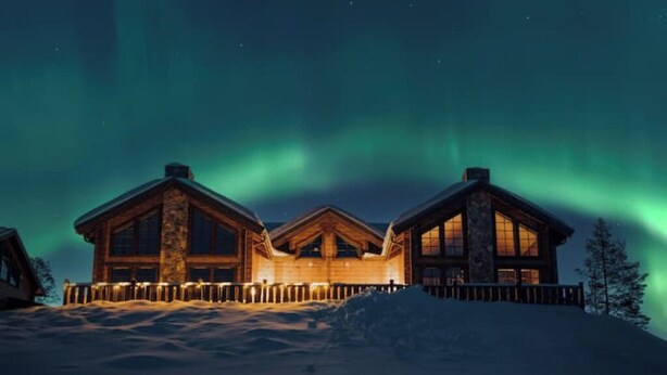 Une cabane en rondins avec une façade en pierre et de grandes fenêtres, entourée de neige.