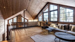 Un vaste espace de vie de style loft, doté d’un plafond en pente, de grandes fenêtres, d’un plancher en bois, d’un canapé et d’une table basse.