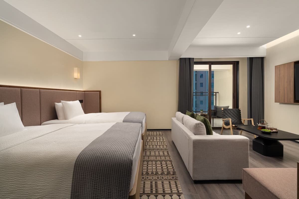 Een hotelkamer met een groot bed, een bank, een bureau en uitzicht op een gebouw.