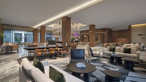 Un hall amplio con zona de estar central, mostrador de recepción y ventanas grandes.
