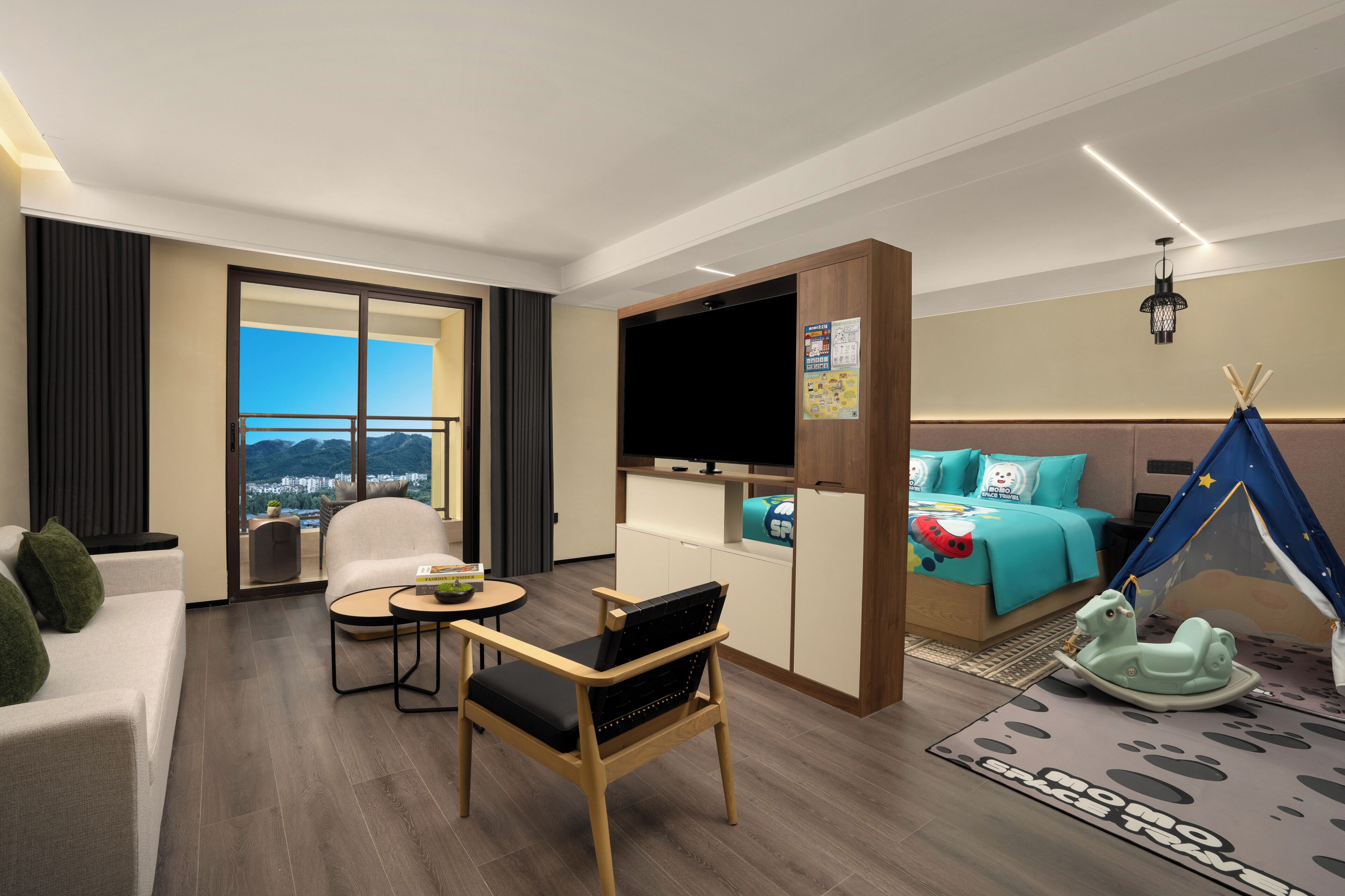 A modern hotel room with a sofa, a chair, a small table, a bed with a tent, a television, and a view of the city.