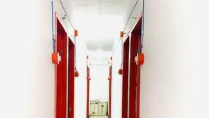 A corridor with red doors, white walls, and a tiled floor. - WJV INN CARCAR (Carcar)