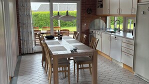 A modern kitchen with a dining area, large windows, and a view of the outdoors. - Lovely holiday home near beach and nature (Karrebæksminde)