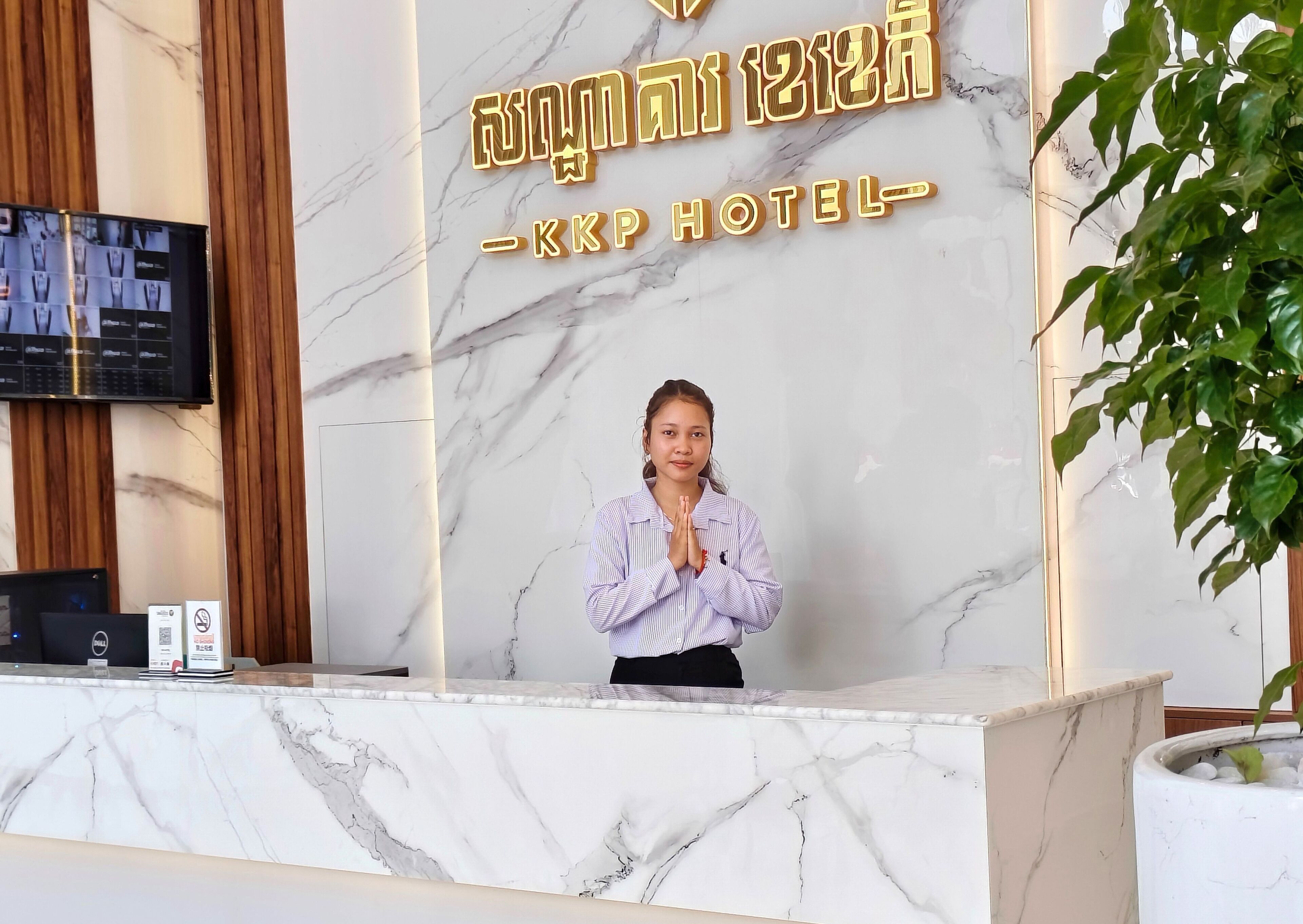 A hotel reception desk with a marble counter and a digital screen displaying room options.