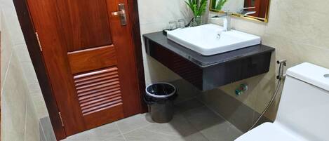 A bathroom with a wooden door, a white sink, a black vanity, a toilet, and a mirror.
