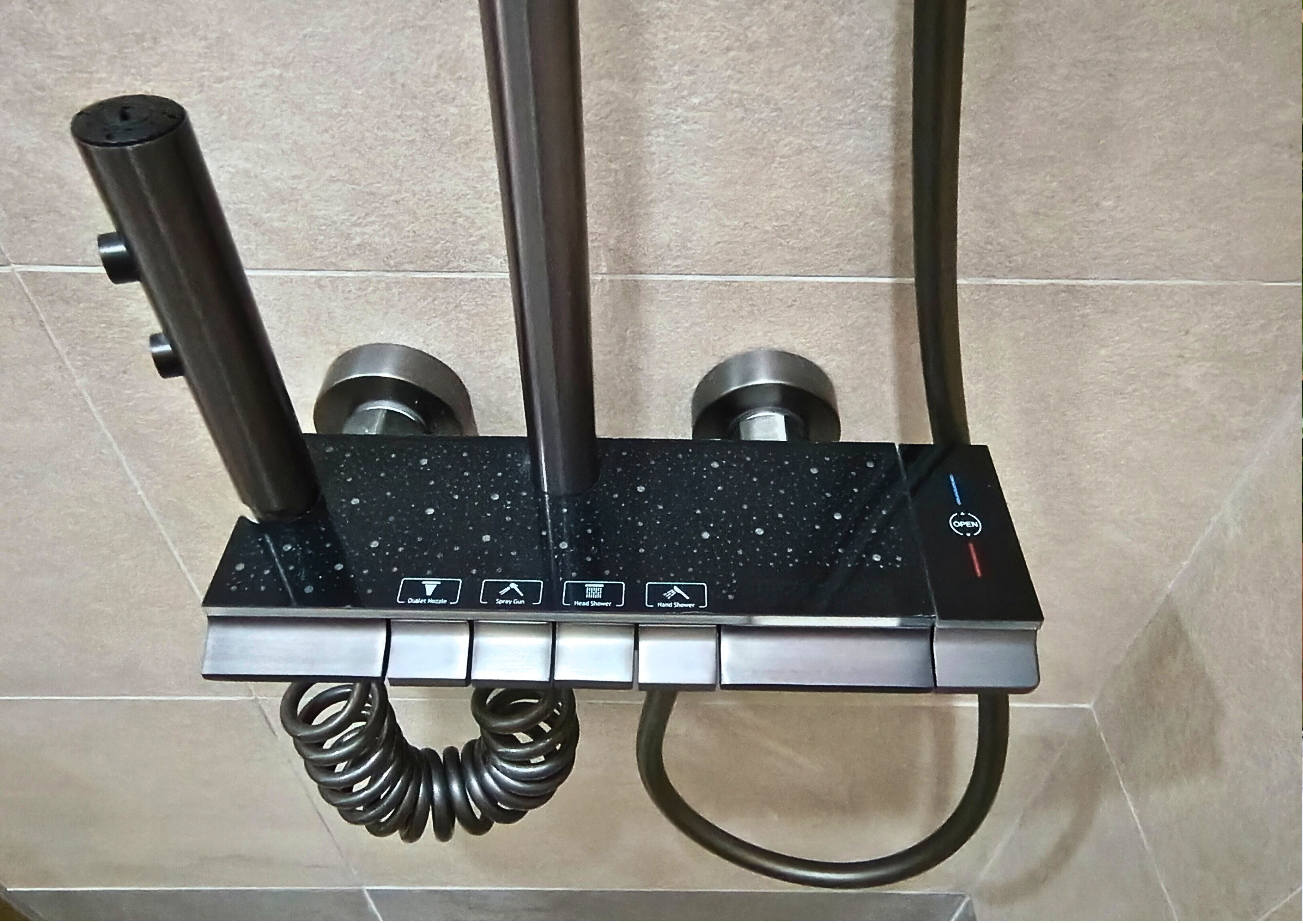 Un panel de control de ducha con múltiples opciones de flujo de agua, que incluye un cabezal de ducha de mano y un plato de ducha.