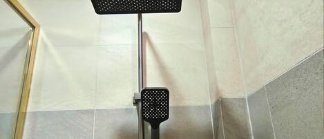 A shower with a rectangular head and a handheld attachment.
